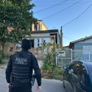 Policial civil em frente a residência durante cumprimento de mandados