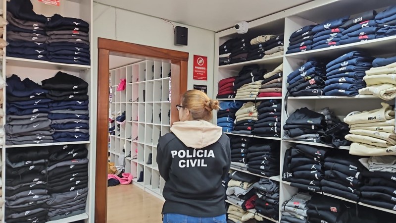 Policial civil junto a itens de roupas em uma sala 