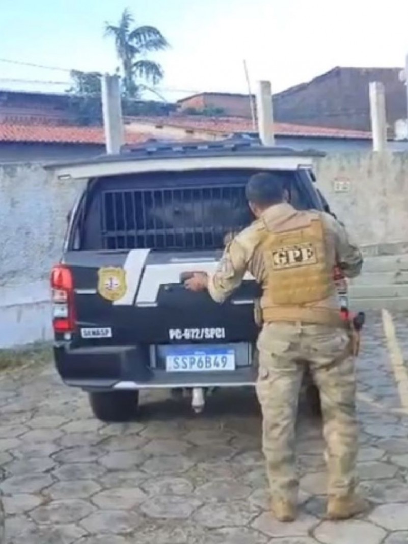 Policial civil do Maranhão com farda bege em frente a viatura policial preta