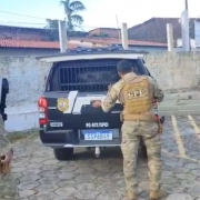 Policial civil do Maranhão com farda bege em frente a viatura policial preta