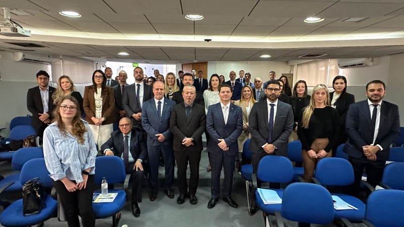 Pessoas em pé posadas para foto com algumas cadeiras à frente