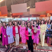 Dezenas de mulheres em pé, vestindo majoritariamente rosa, posadas para foto coletiva