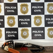 Itens expostos em cima de mesa com banner da Polícia Civil ao fundo