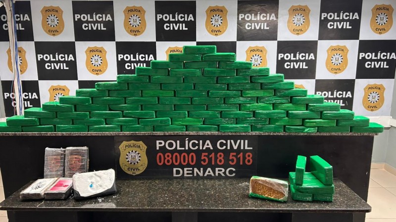 Tabletes brancos e verdes dispostos em cima de uma mesa com banners da Pol&iacute;cia Civil ao fundo