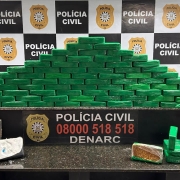 Tabletes brancos e verdes dispostos em cima de uma mesa com banners da Pol&iacute;cia Civil ao fundo