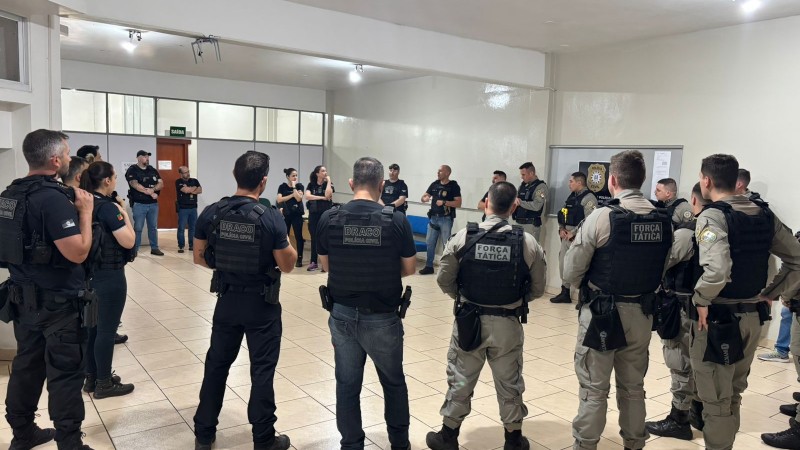 Policiais civis e militares em um c&iacute;rculo dentro de uma sala com paredes brancas