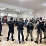 Policiais civis e militares em um c&iacute;rculo dentro de uma sala com paredes brancas