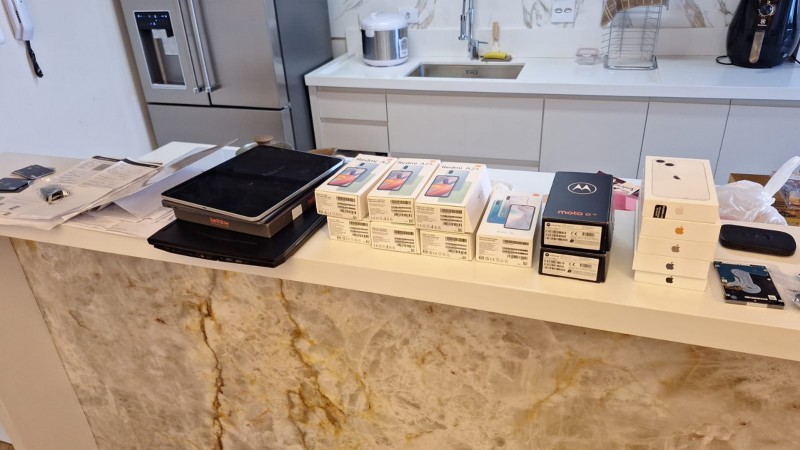 Aparelhos eletr&ocirc;nicos e caixas de eletr&ocirc;nicos expostos em bancada de cozinha no local da apreens&atilde;o