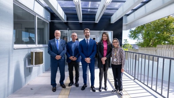 Homens e mulheres posados para fotos embaixo de cobertura mostrando parte de obras